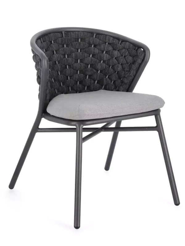 Πολυθρόνα εξωτερικού χώρου Harlow με σκούρο μεταλλικό σκελετό και υφασμάτινο μαξιλάρι σε ρουστίκ περιβάλλον.